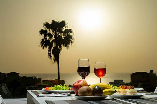 Mesa con recetas canarias al atardecer, frente al mar y una palmera.