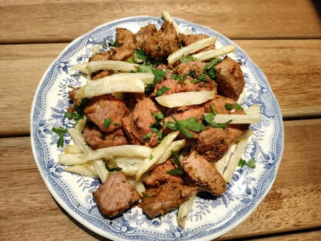 Plato de carne fiesta canaria con papas fritas y perejil picado. Un clásico de la cocina canaria.