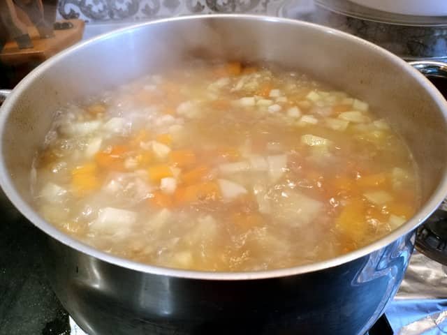 Incorporar verduras al potaje de lentejas canario y vegano durante su preparación.