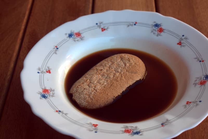 Bizcocho de soletilla siendo remojado en café azucarado para hacer el postre Príncipe Alberto..