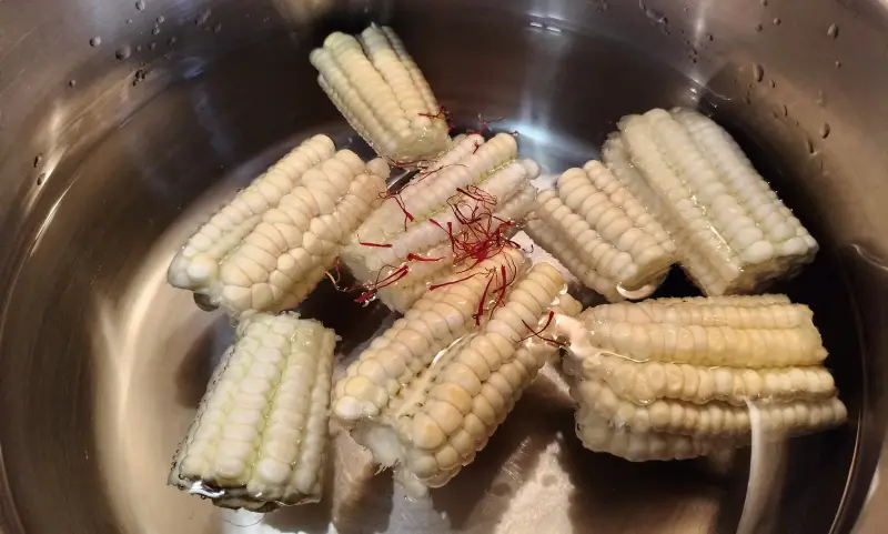 Un caldero con agua, piñas de millo y azafrán