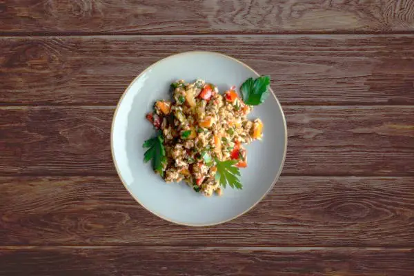 Un plato de arroz con verduras sobre una mesa de madera oscura
